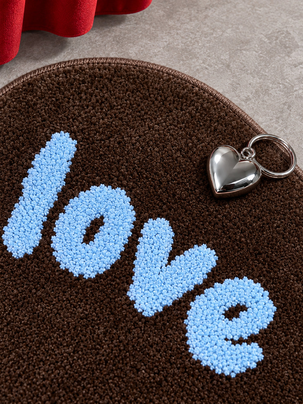 Close-up of the brown heart-shaped accent rug's blue tufted lettering