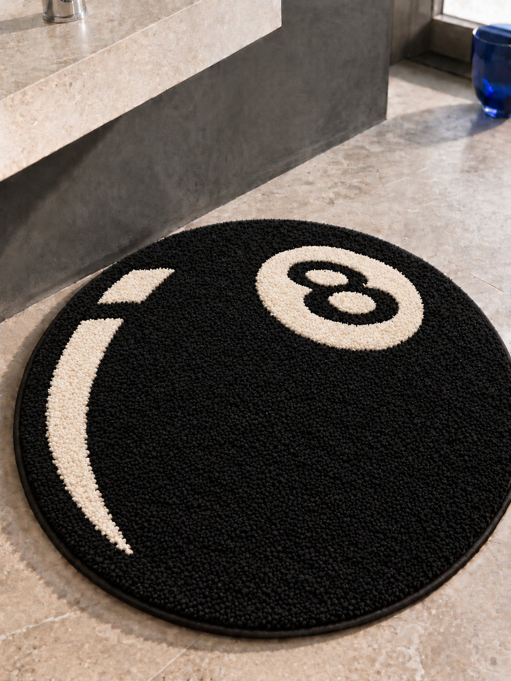 Black eight-ball round rug, 80 cm diameter, shown from above at a bathroom vanity.