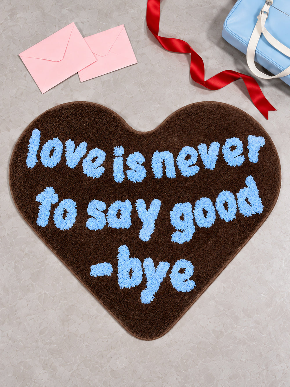 Brown heart-shaped accent rug with pink envelopes and red ribbon