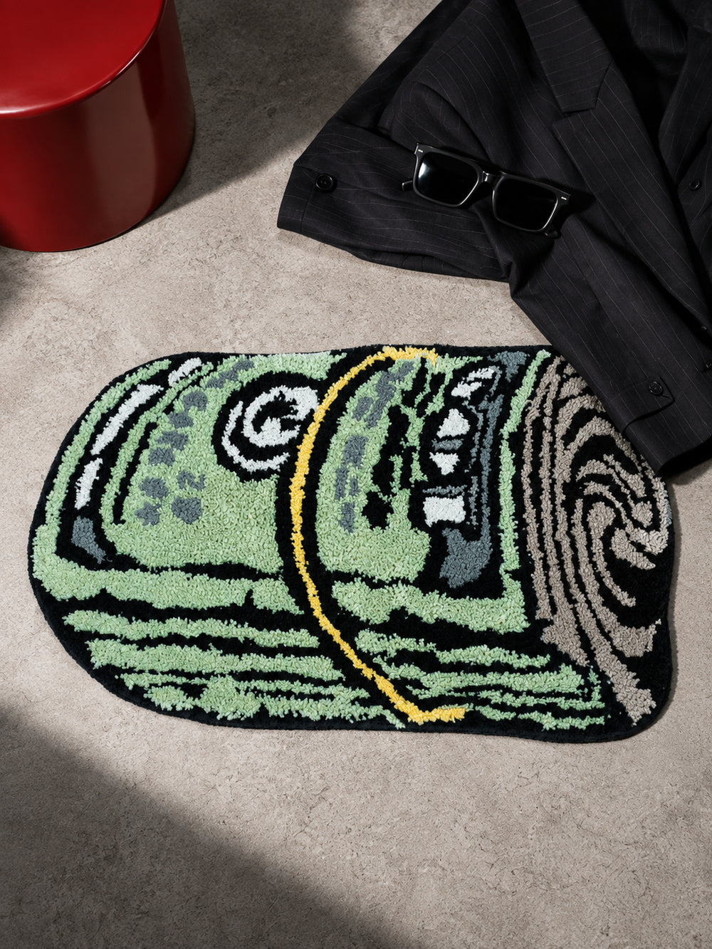 Rolled Cash Bath Mat on the floor beside a black jacket and sunglasses