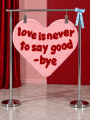 Pink heart-shaped accent rug hanging from a display rail