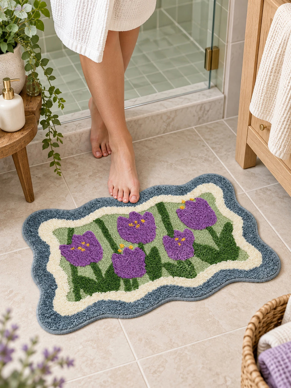 Violet Tulip Frame Wavy-Edge Bath Mat on a bathroom floor by a shower