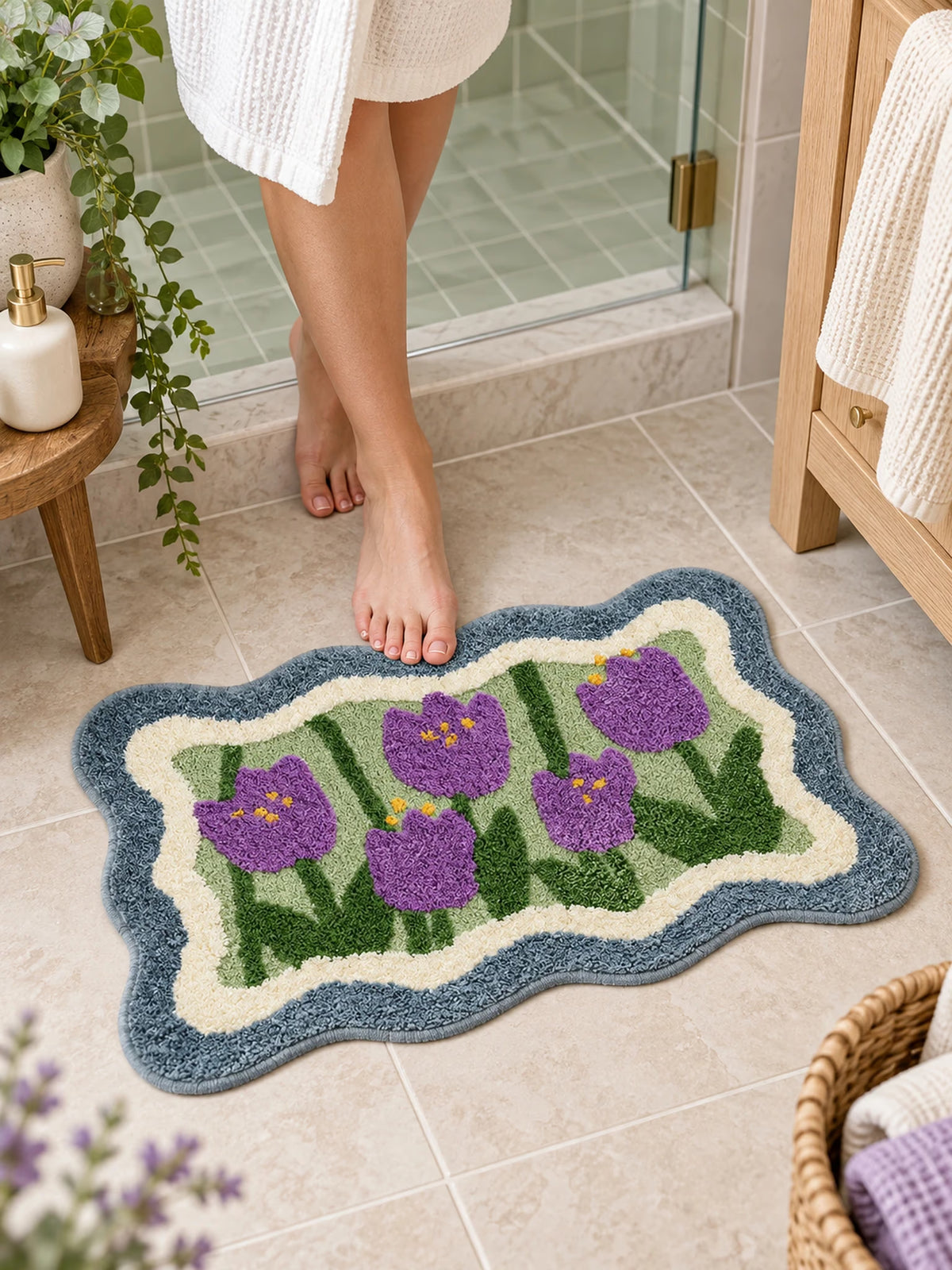 Violet Tulip Frame Wavy-Edge Bath Mat on a bathroom floor by a shower