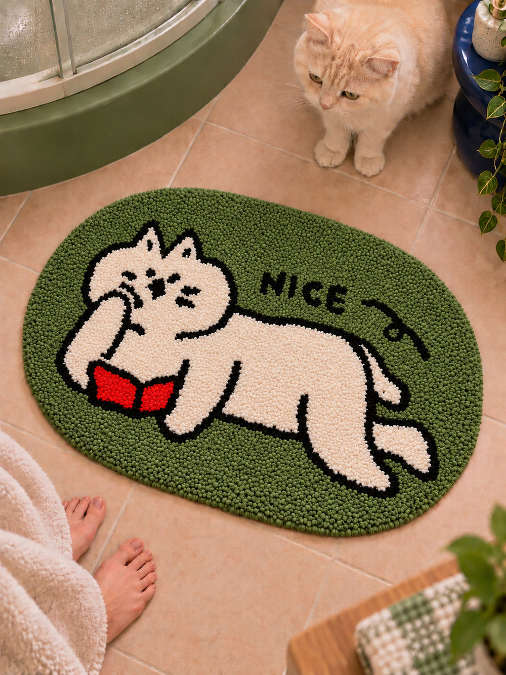 Green reading-cat oval mat, 50 x 80 cm, viewed from above beside a cat on a bathroom floor.