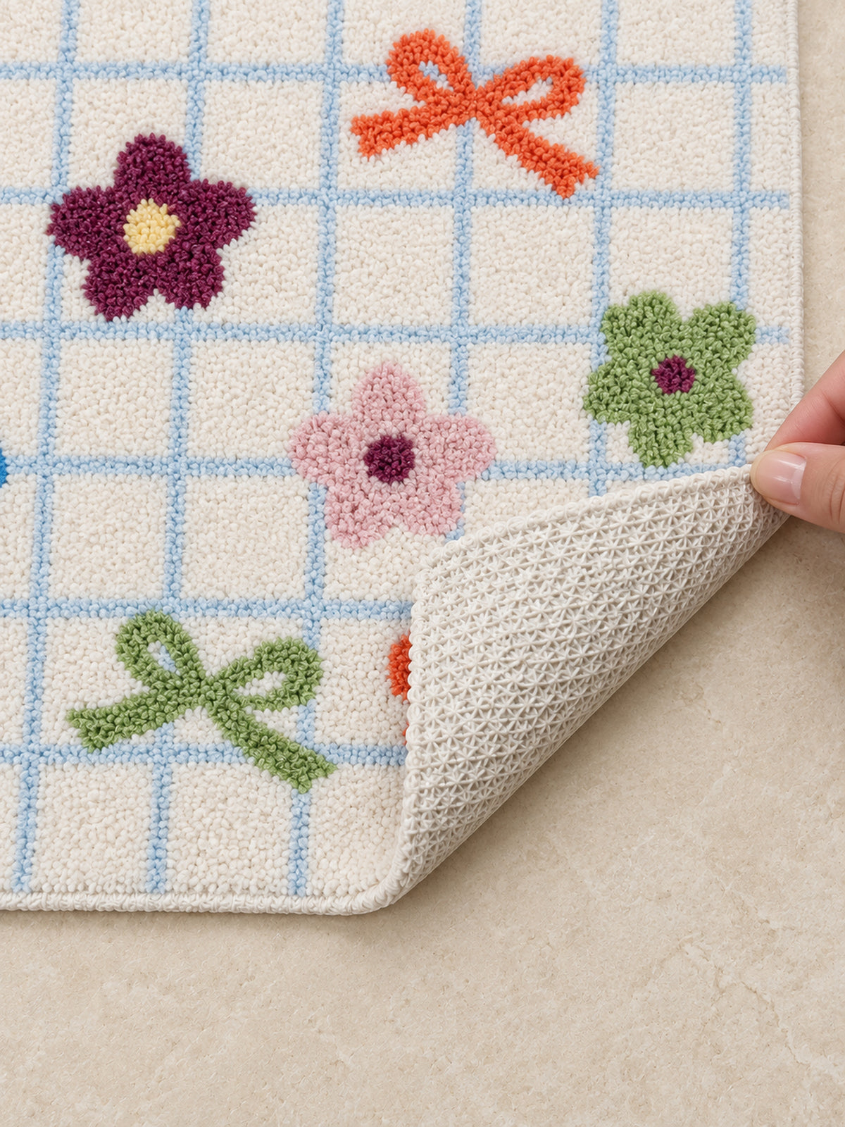 Garden Bows and Blooms checkered mat, 50 x 80 cm, with an edge lifted to show the pale patterned backing.