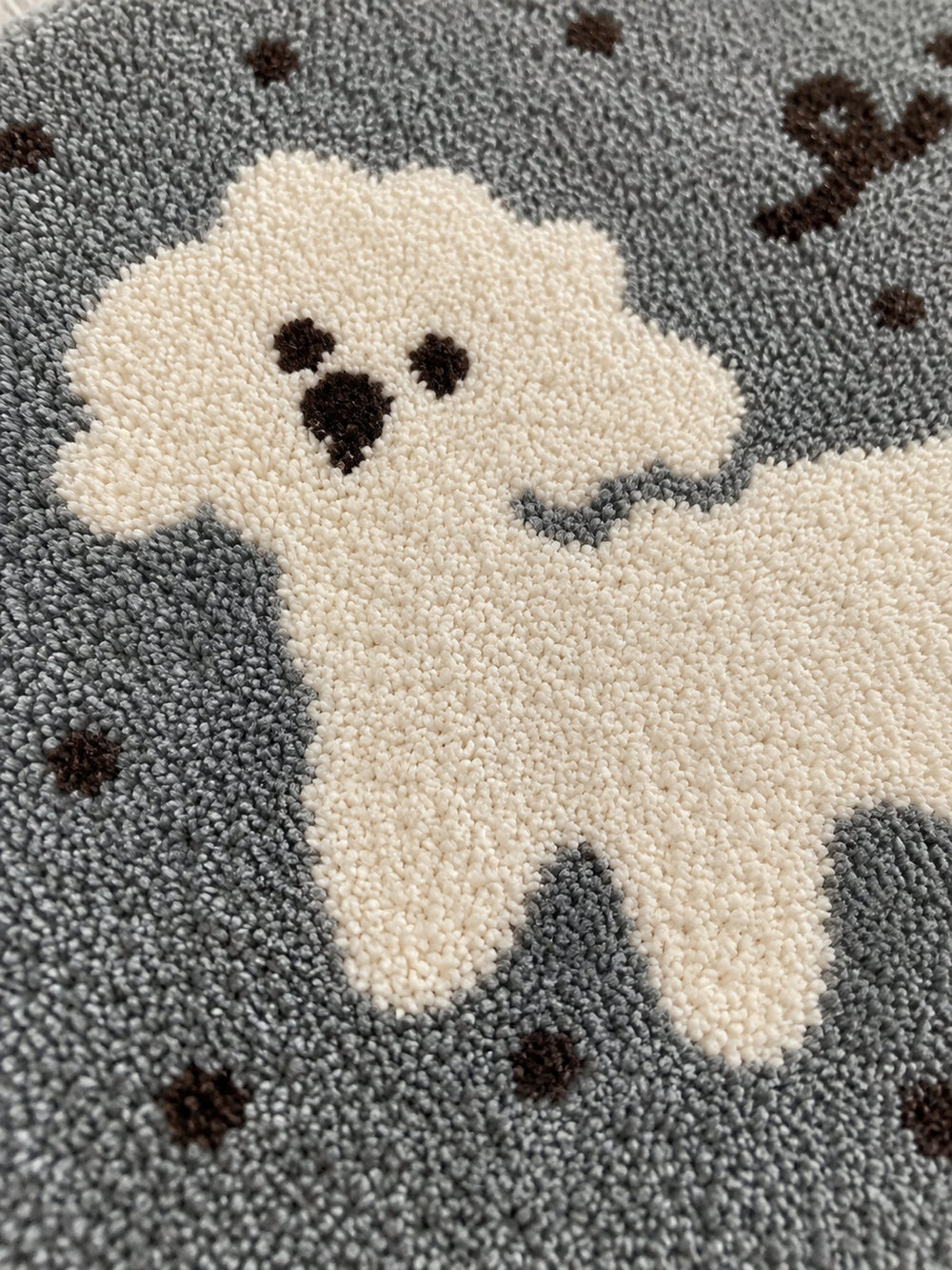 Gray polka-dot pup oval mat, 50 x 80 cm, close-up of the cream dog motif and textured gray surface.