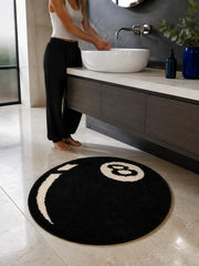 Black eight-ball round rug, 80 cm diameter, at a bathroom vanity beside a person.