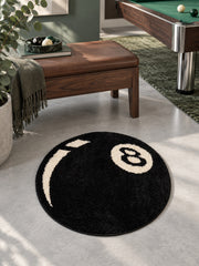 Black eight-ball round rug, 40 cm diameter, beside a wooden bench and pool table.