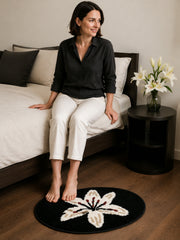 Midnight Lily Oval Bath Mat beside a bed