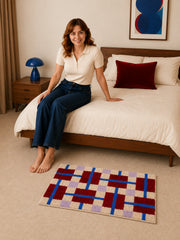 Crimson Grid Colorblock Bath Mat beside a bed