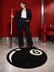 Black eight-ball round rug, 80 cm diameter, beside a person holding a pool cue in a red room.
