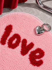 Close-up of the pink heart-shaped accent rug's red tufted lettering
