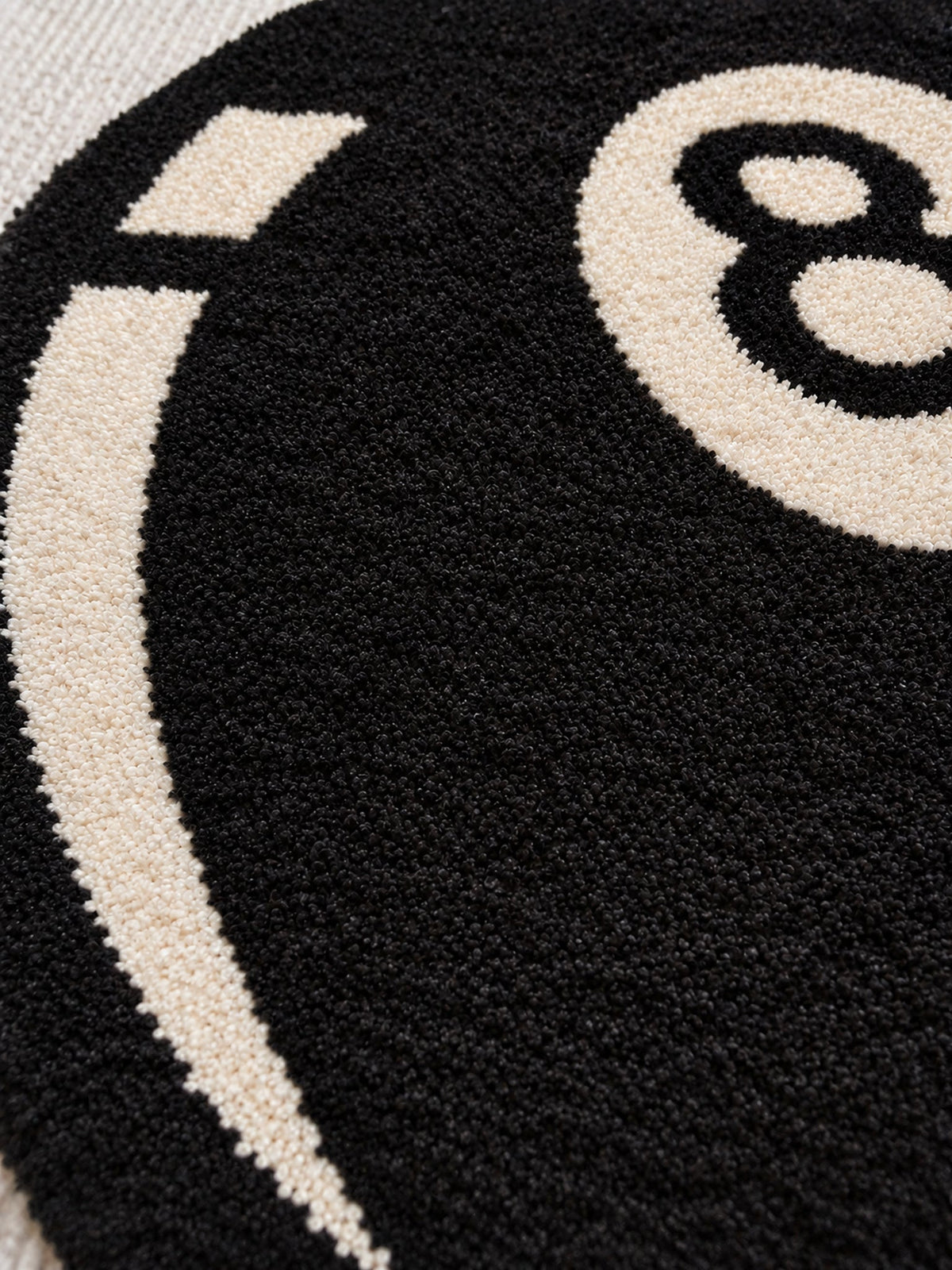 Black eight-ball round rug, 40 cm diameter, close-up of the black pile and ivory graphic.