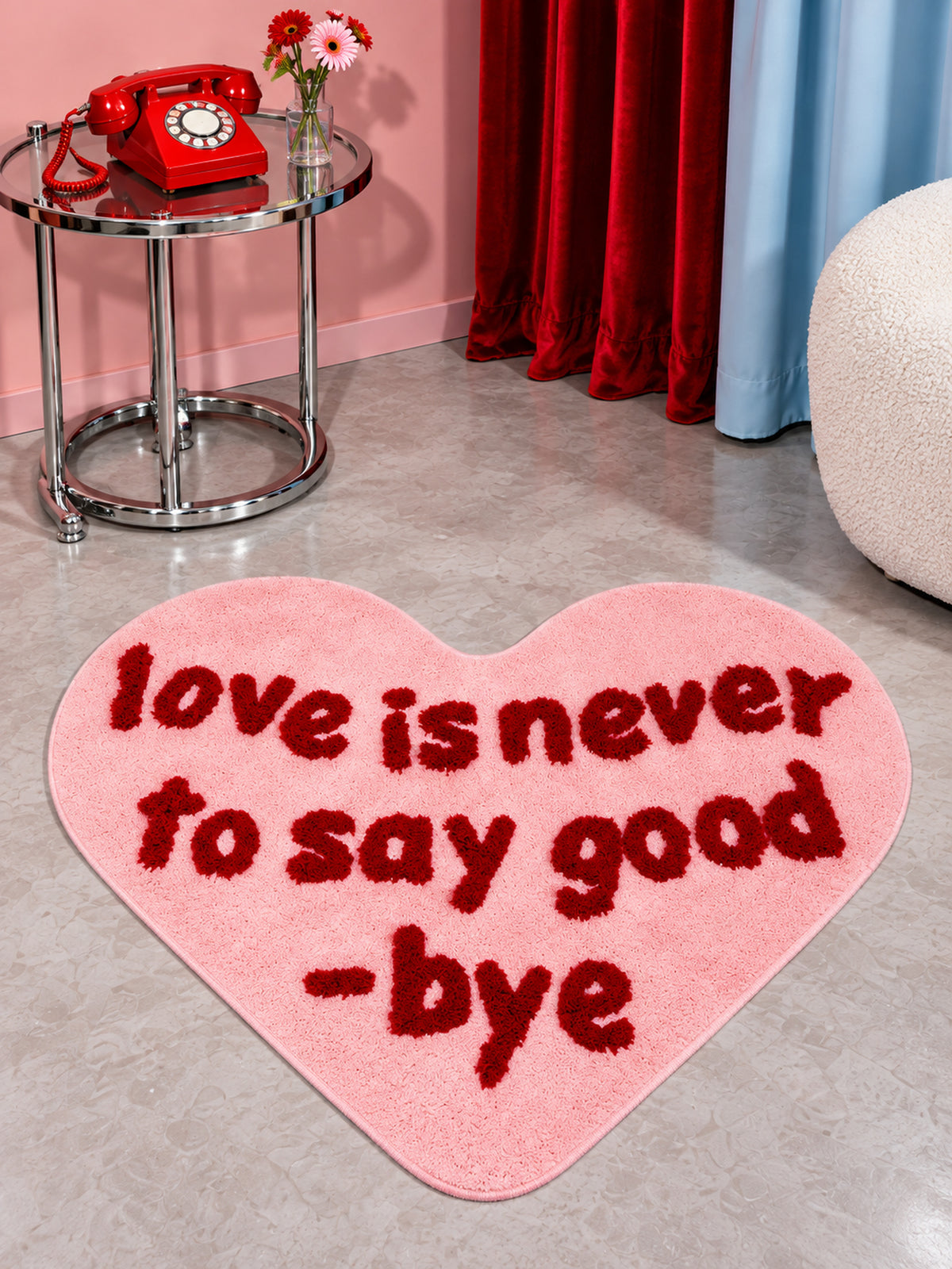 Pink heart-shaped accent rug beside a red telephone and side table