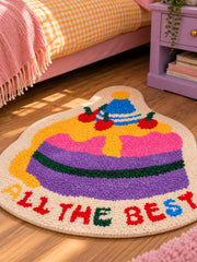 Best Wishes Cake Shaped Bath Mat beside a bed, shown from another angle