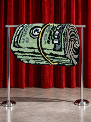Rolled Cash Bath Mat displayed over a rail against red curtains