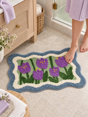 Violet Tulip Frame Wavy-Edge Bath Mat on a bathroom floor beside a vanity