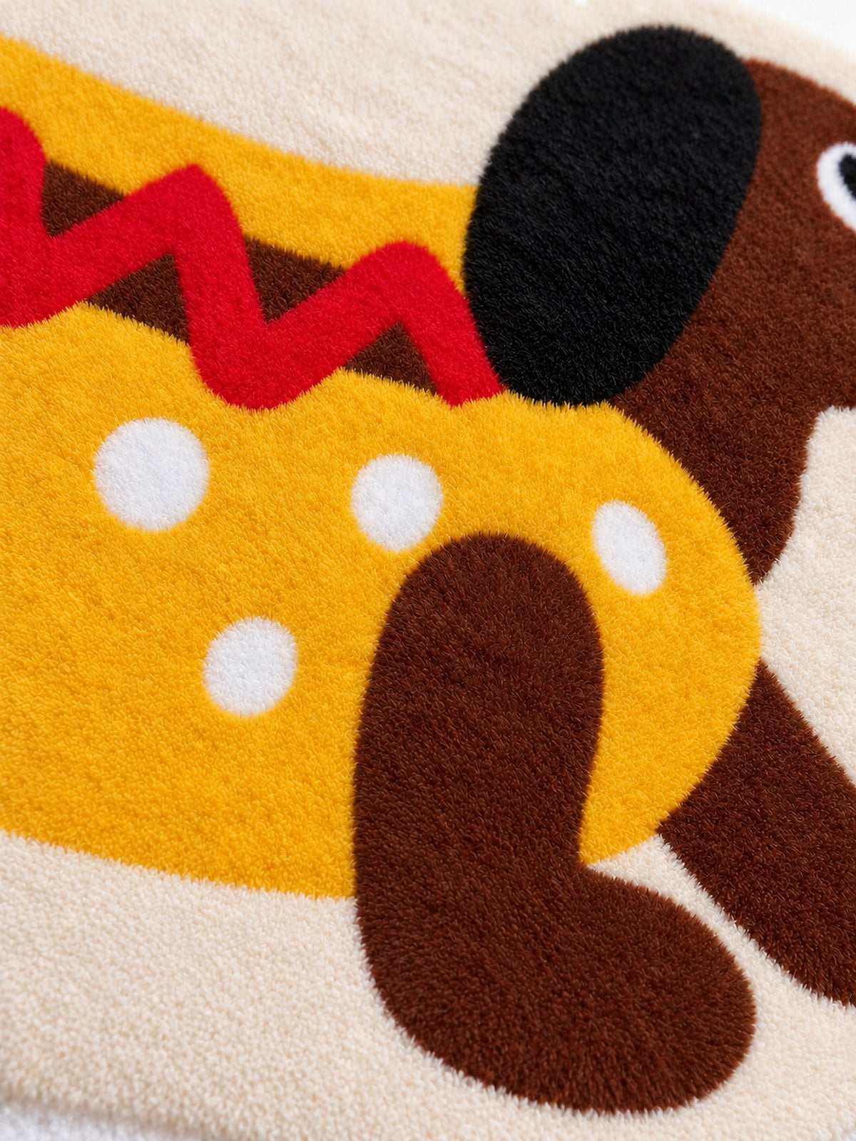 Hot dog dachshund-shaped rug, 80 x 160 cm, close-up of the yellow body, red zigzag and brown leg.