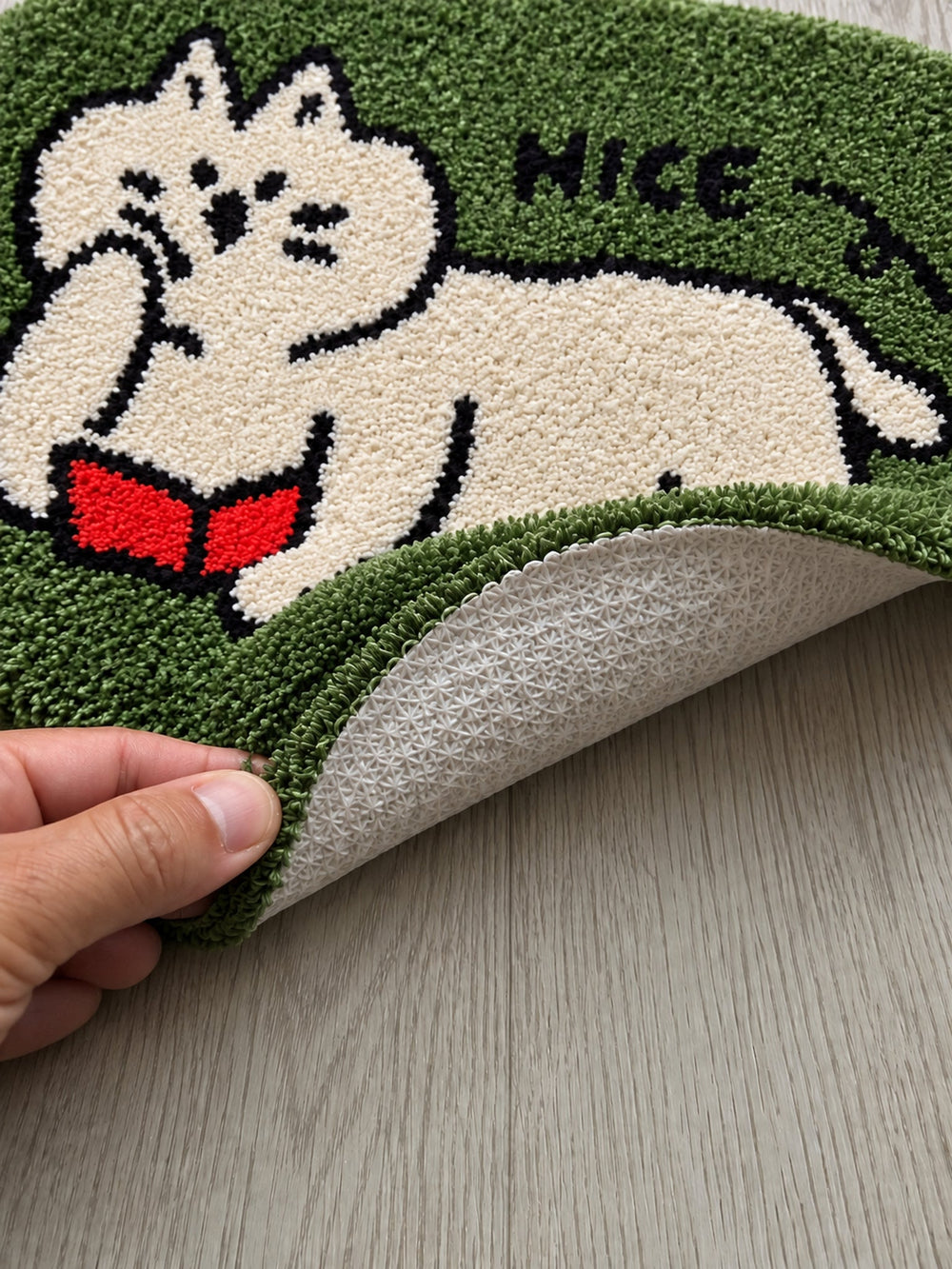 Green reading-cat oval mat, 50 x 80 cm, with one edge lifted to show the pale patterned backing.
