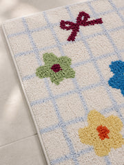 Garden Bows and Blooms checkered mat, 50 x 80 cm, close-up of colorful bows, flowers and blue grid lines.