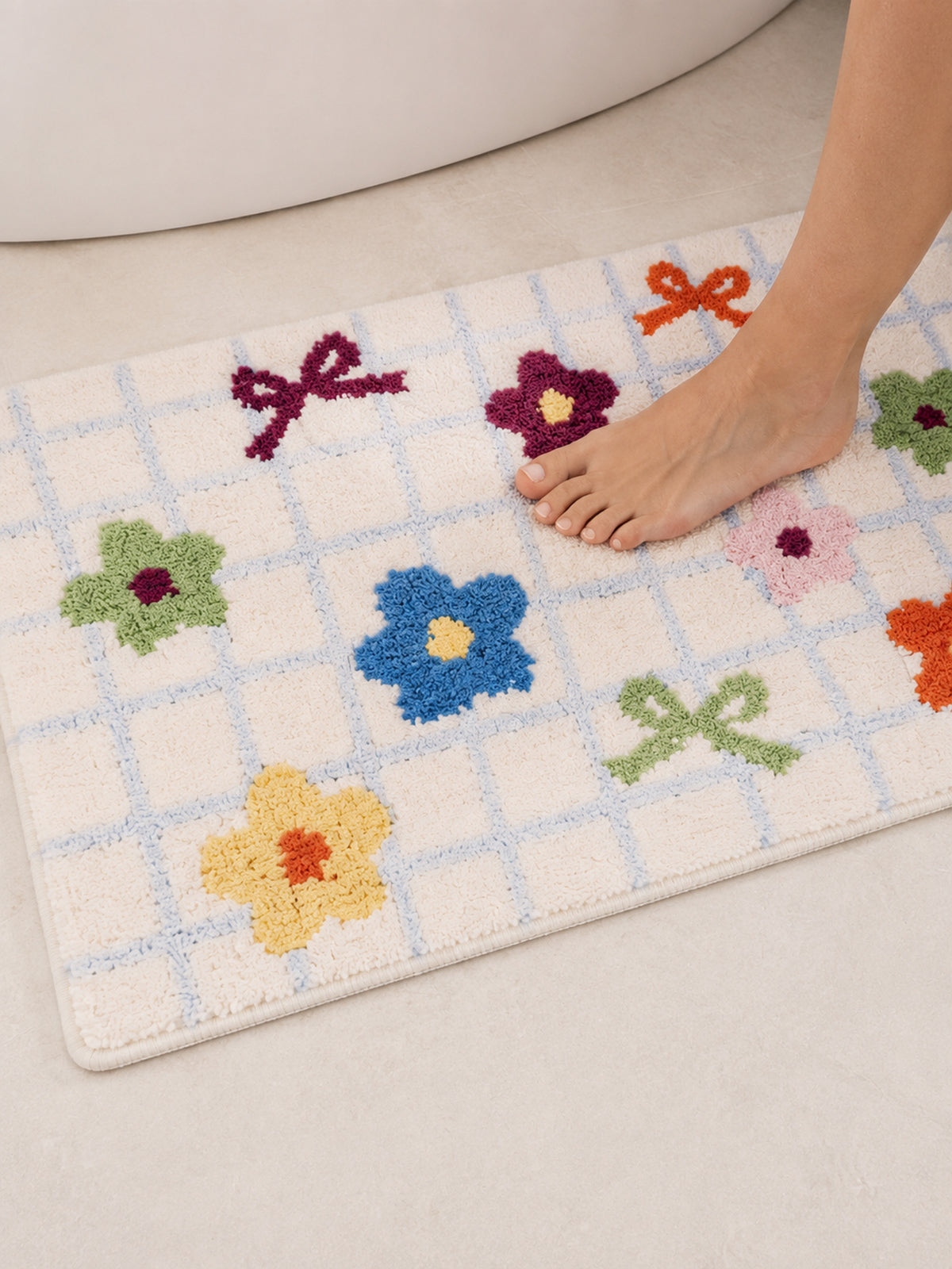 Garden Bows and Blooms checkered mat, 50 x 80 cm, close view beneath bare feet beside a white bathtub.