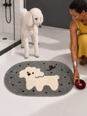 Gray polka-dot pup oval mat, 50 x 80 cm, beside a white poodle and a person reaching for a toy.