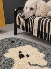 Gray polka-dot pup oval mat, 50 x 80 cm, close view beside a striped bed with a resting poodle.